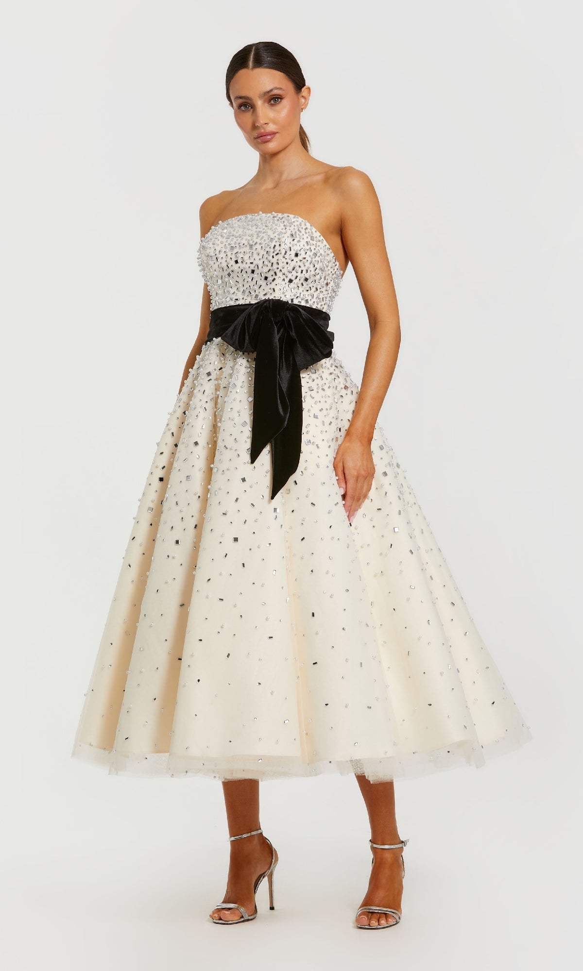 Woman wearing a strapless white dress with black bow and polka dot pattern on a white background